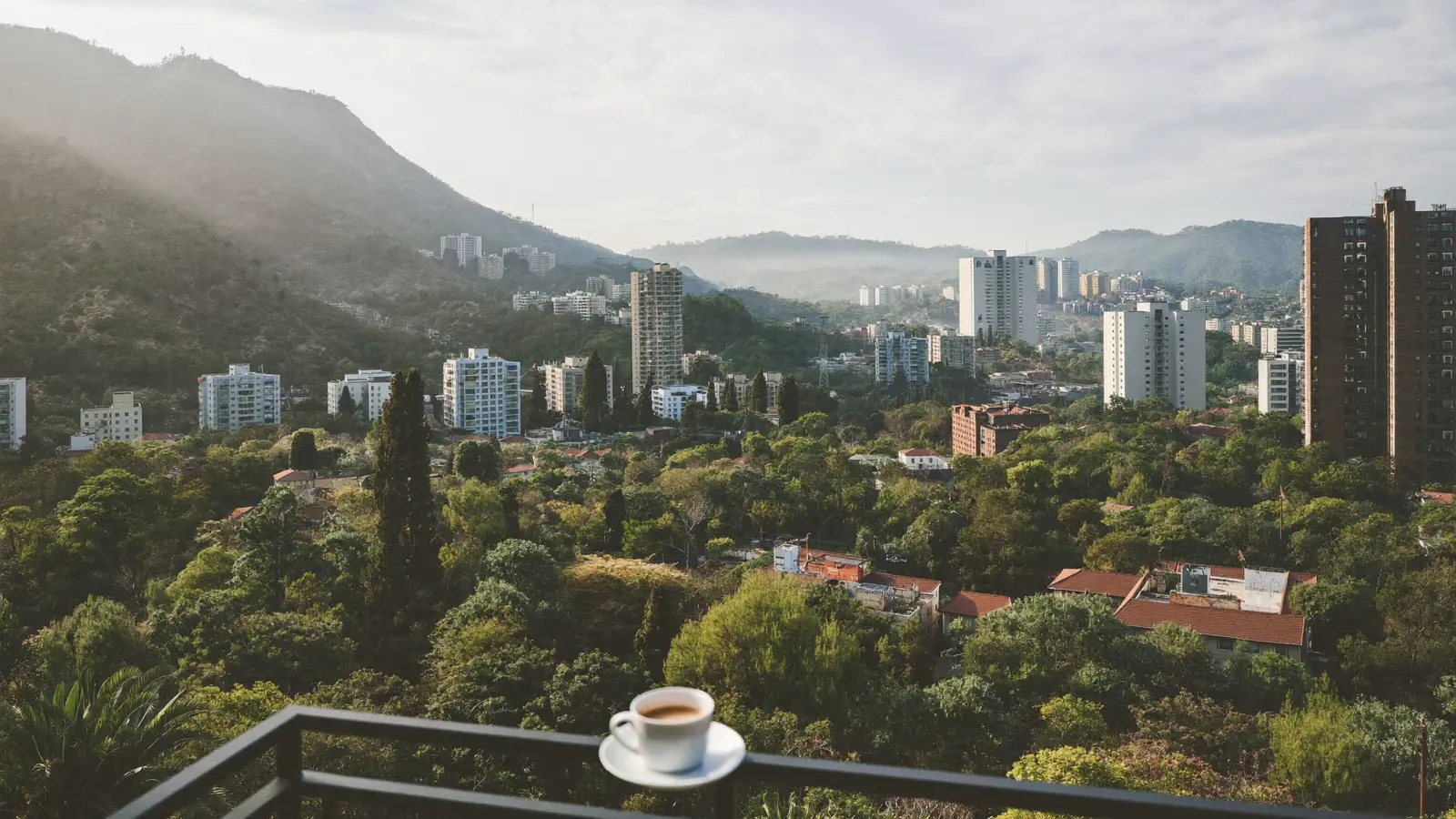 Early morning view over Medellín’s valley and towers from a balcony, a cup of coffee on the rail