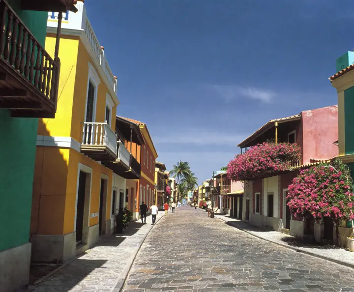 A cobblestone street of colorful colonial houses with bougainvillea-covered balconies in Cartagena's old city