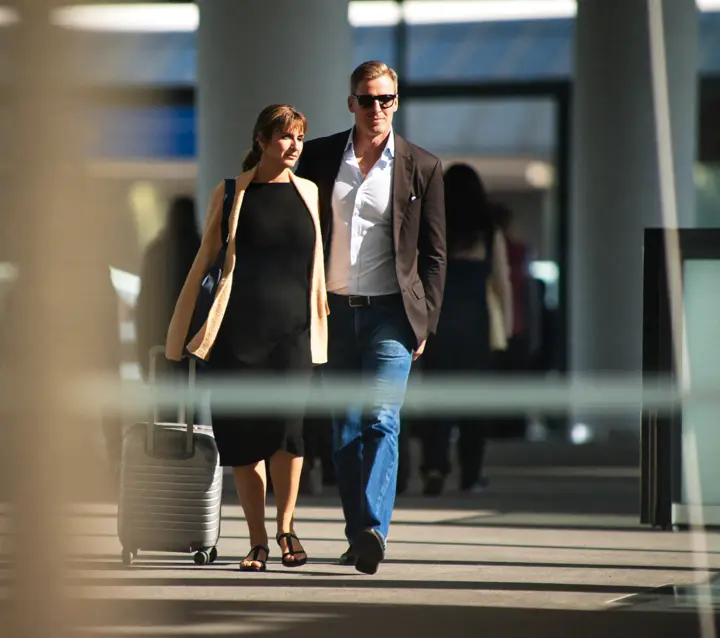 A couple walking through an airport terminal with a small rolling suitcase