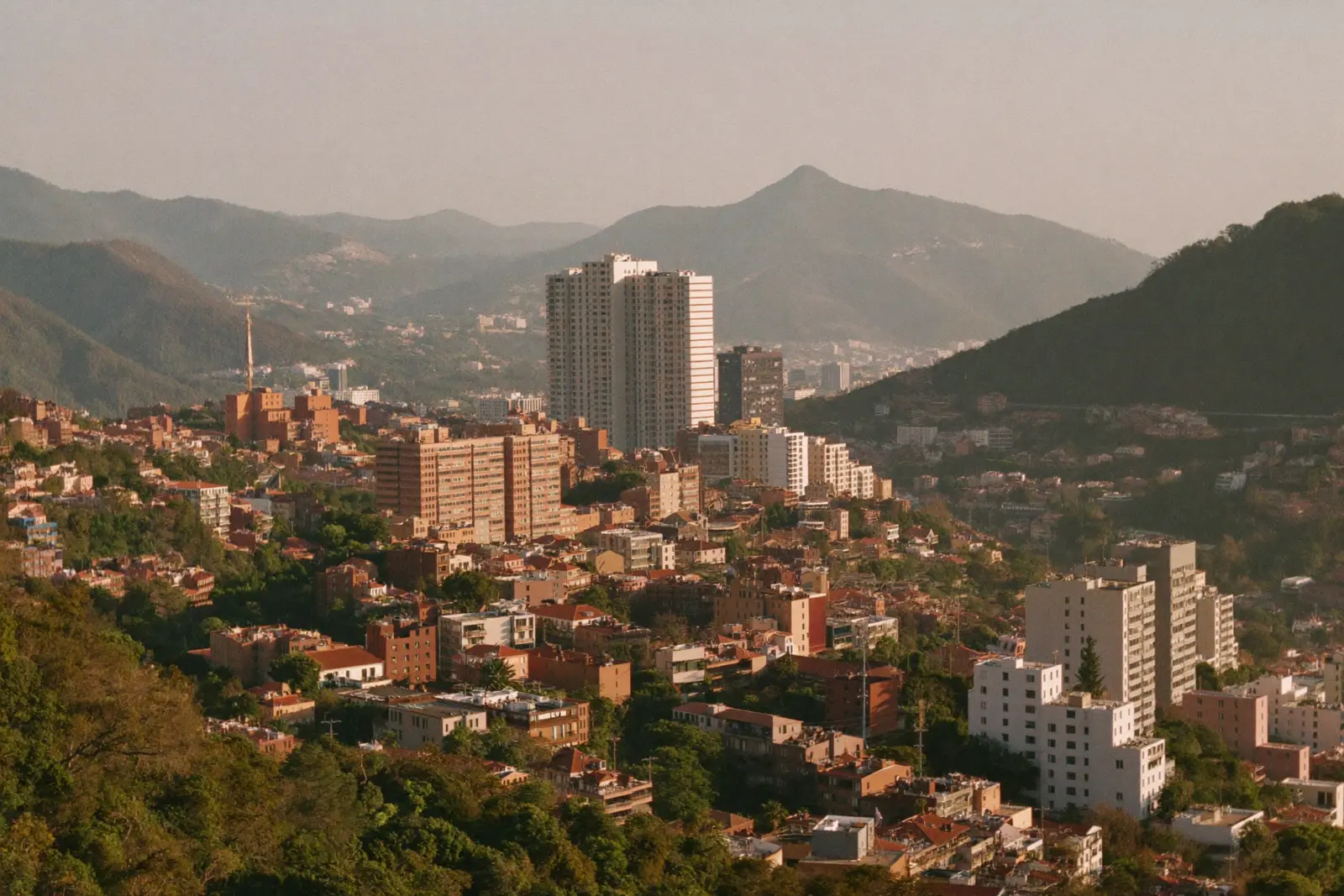 Medellín's red-brick neighborhoods and towers climbing the green Aburrá Valley at golden hour