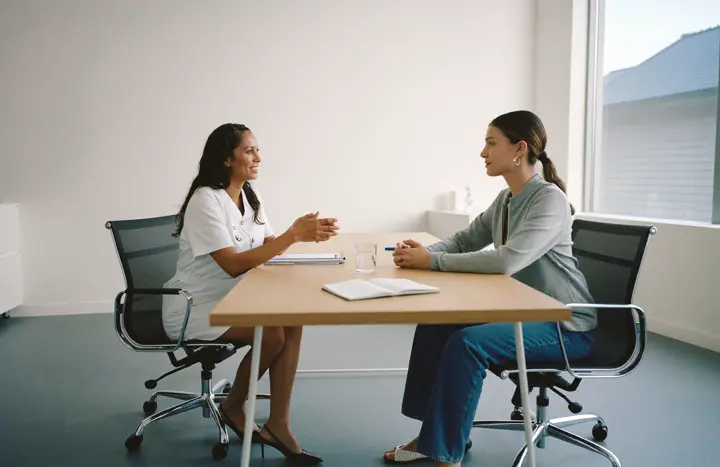 A surgeon and a patient in a private consultation across a wooden desk