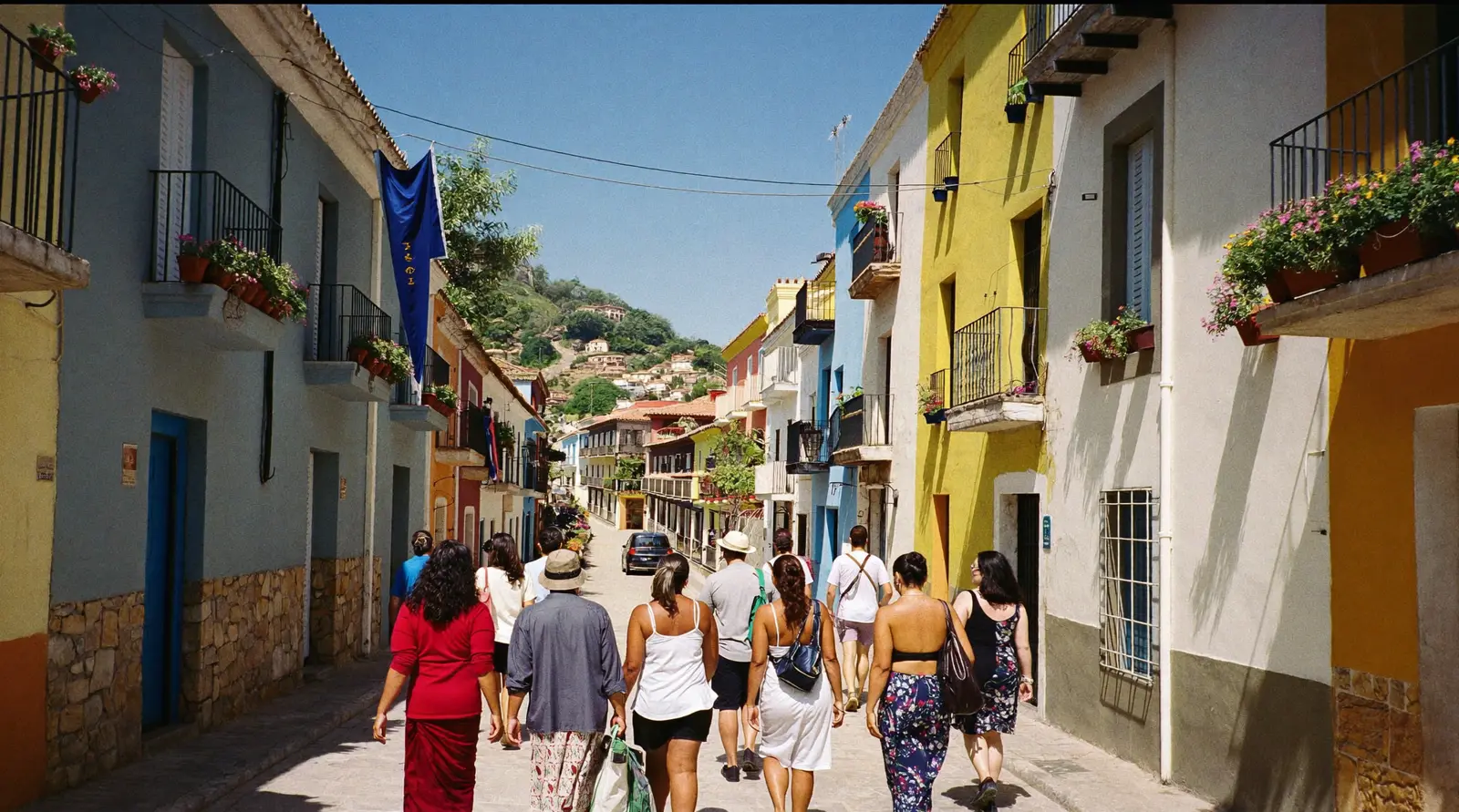 A small group of travelers walking up a colorful village street with painted balconies